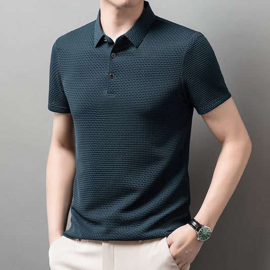 Mann trägt dunkelblaues Polohemd mit Strukturmuster, kombiniert mit beiger Hose. Elegante Herrenmode, modernes Design, Freizeitkleidung.