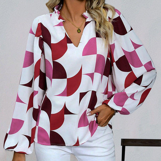 Frau trägt modische Bluse mit geometrischem Muster in Rot und Rosa, kombiniert mit weißer Hose. Elegantes Outfit, ideal für Freizeit und Büro.