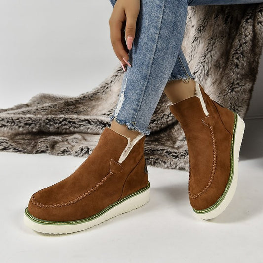 Damenstiefel aus braunem Wildleder mit weißer Sohle, getragen mit blauen Jeans. Modische Winterstiefel, bequem und stilvoll für kalte Tage.