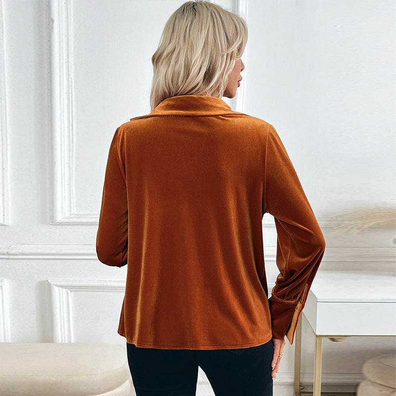 Frau in orangefarbenem Samtoberteil, Rückansicht, vor weißer Wand. Modetrend, elegantes Damenoutfit, Herbstmode, stilvolle Kleidung.
