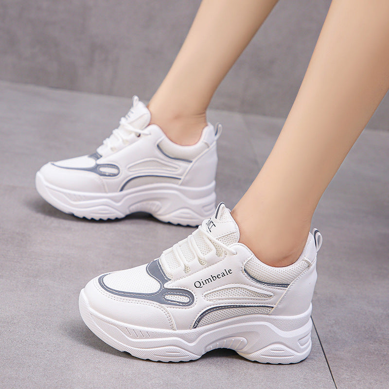 Weiße Damen-Sneaker mit dicker Sohle, grauen Akzenten und Schnürung auf grauem Hintergrund. Modische Sportschuhe für Alltag und Freizeit.