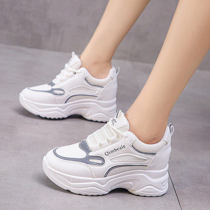 Weiße Damen-Sneaker mit dicker Sohle, grauen Akzenten und Schnürung auf grauem Hintergrund. Modische Sportschuhe für Alltag und Freizeit.