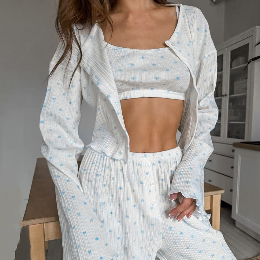 Frau in weißem, gepunktetem Pyjama-Set mit bauchfreiem Top in moderner Küche. Bequeme Nachtwäsche, modischer Schlafanzug, Damenmode.