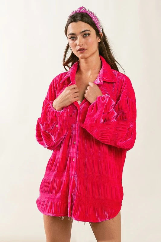 Frau in leuchtend pinker, plissierter Bluse und passendem Haarband. Modetrend, Damenmode, auffällige Kleidung, stilvolles Outfit.