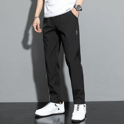 Mann trägt schwarze Chinohose, weißes T-Shirt und weiße Sneaker. Stilvolle Herrenmode, lässiger Look, moderne Kleidung, Freizeitoutfit.