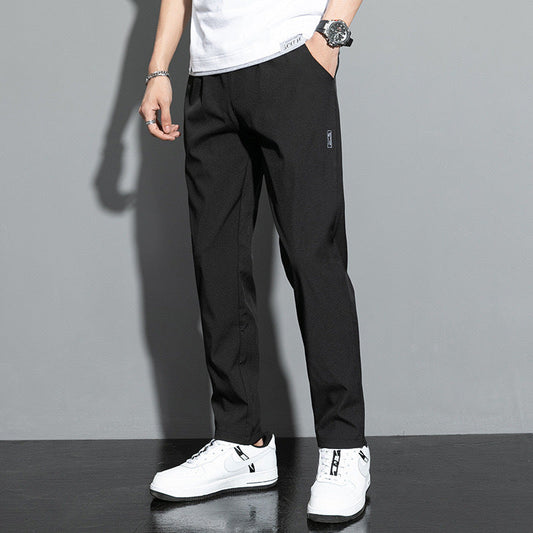 Mann trägt schwarze Chinohose, weißes T-Shirt und weiße Sneaker. Stilvolle Herrenmode, lässiger Look, moderne Kleidung, Freizeitoutfit.
