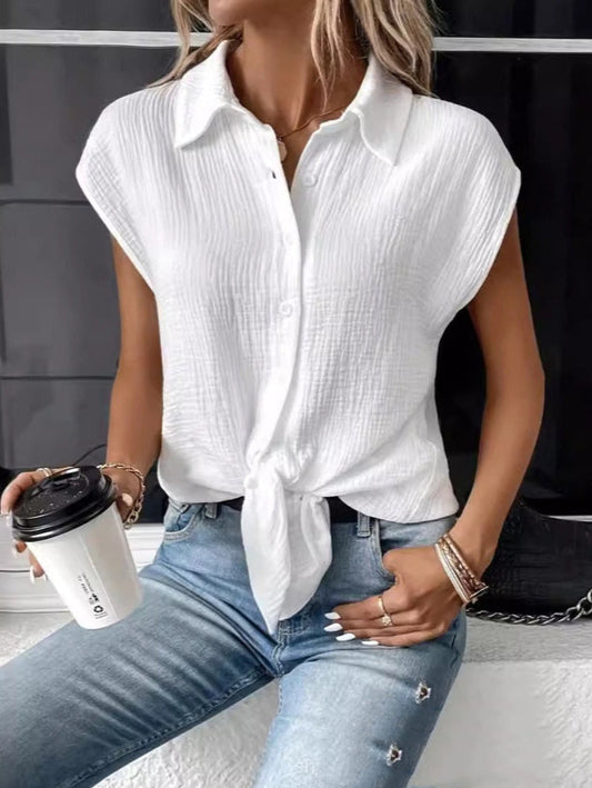 Frau in weißer Bluse mit Knoten, blaue Jeans, hält Kaffeebecher. Modetrend, lässiger Sommerlook, Damenmode, Streetstyle, Accessoires.