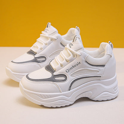 Weiße Damen-Sneaker mit dicker Sohle, grauen Akzenten und Mesh-Einsätzen vor gelbem Hintergrund. Modische Sportschuhe, bequem und trendig.
