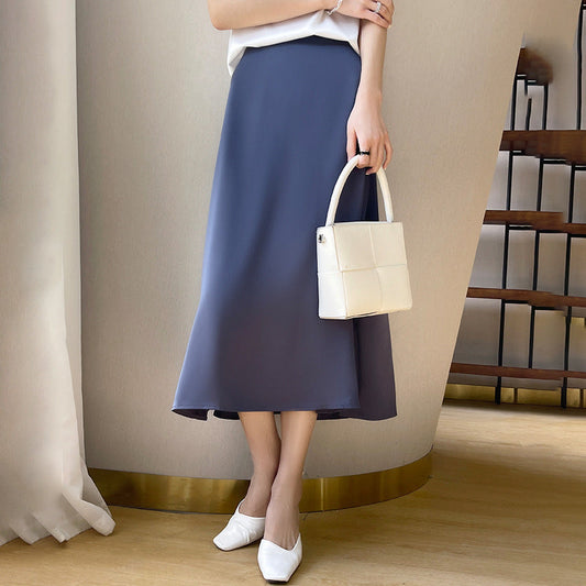 Elegante Frau in blauem Midirock, weißem Top und weißen Schuhen, hält weiße Handtasche. Modetrend, Damenmode, stilvolles Outfit.