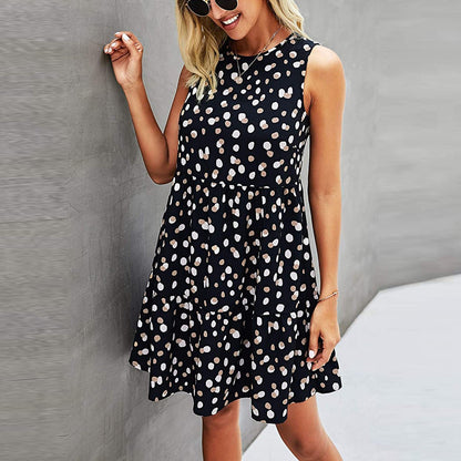 Frau in ärmellosem, gepunktetem Sommerkleid, lächelnd, mit Sonnenbrille, vor grauer Wand. Modetrend, Damenmode, Sommeroutfit.
