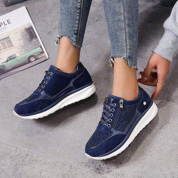 Damen Sneaker in Dunkelblau mit weißer Sohle, Reißverschluss und Schnürsenkeln, getragen mit Jeans. Modische Freizeitschuhe für Frauen.