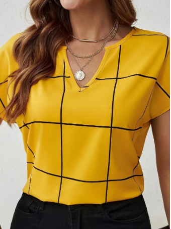 Frau in gelber Bluse mit schwarzem Karomuster, V-Ausschnitt und Halsketten. Modetrend, Damenbekleidung, stilvolles Outfit.