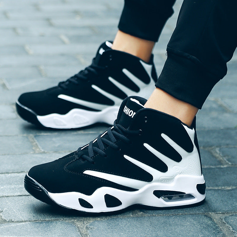 Schwarze und weiße Basketball-Sneaker auf grauem Pflaster, sportliches Design, hohe Knöchelunterstützung, ideal für Streetwear und Sport.