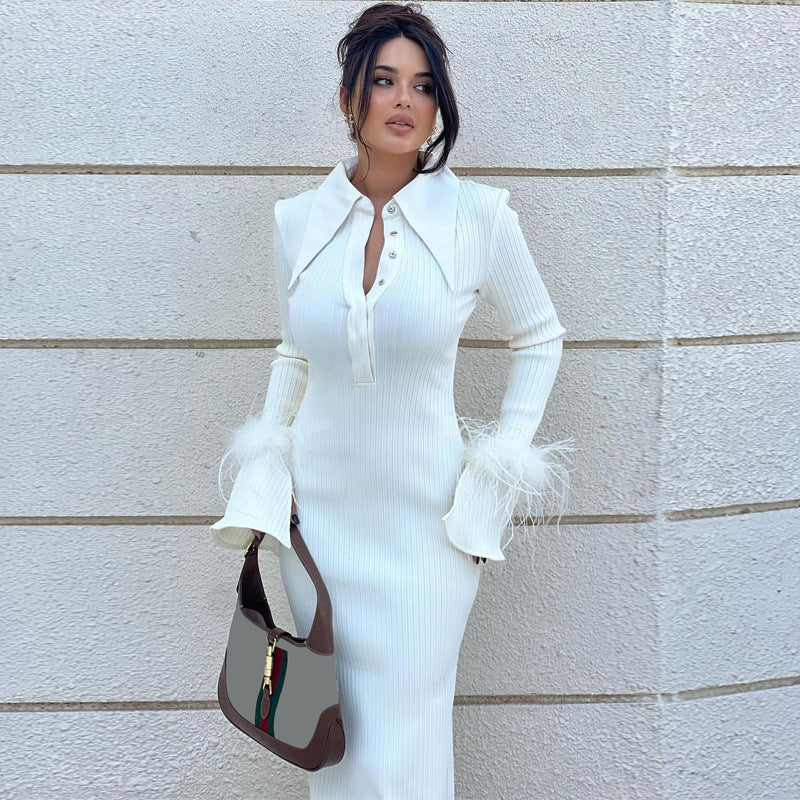Frau in elegantem weißen Kleid mit Federn, hält braune Handtasche, steht vor heller Wand. Modetrend, Damenmode, stilvolles Outfit.
