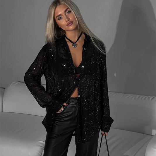 Junge Frau in schwarzer, glitzernder Bluse und Lederhose, steht vor grauer Wand. Modetrend, eleganter Look, Abendmode, stilvolle Kleidung.
