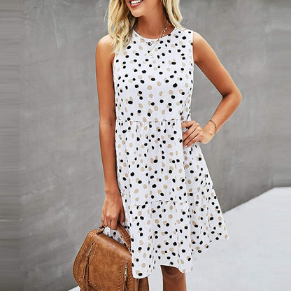 Frau in ärmellosem, weißem Kleid mit schwarzen Punkten, hält braune Handtasche. Sommermode, elegantes Design, trendiges Outfit.