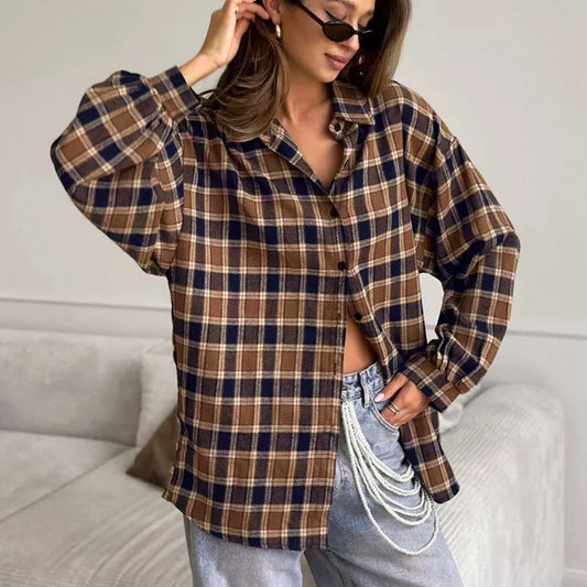 Frau in kariertem Hemd und Jeans mit Perlenkette, modisch und lässig, im Wohnzimmer. Trendige Herbstmode, stilvolle Freizeitkleidung.