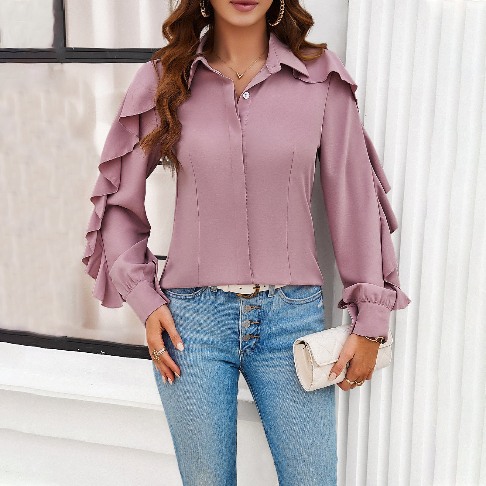 Frau in rosa Rüschenbluse und blauer Jeans, hält weiße Clutch. Modetrend, elegante Damenmode, stilvolle Freizeitkleidung.