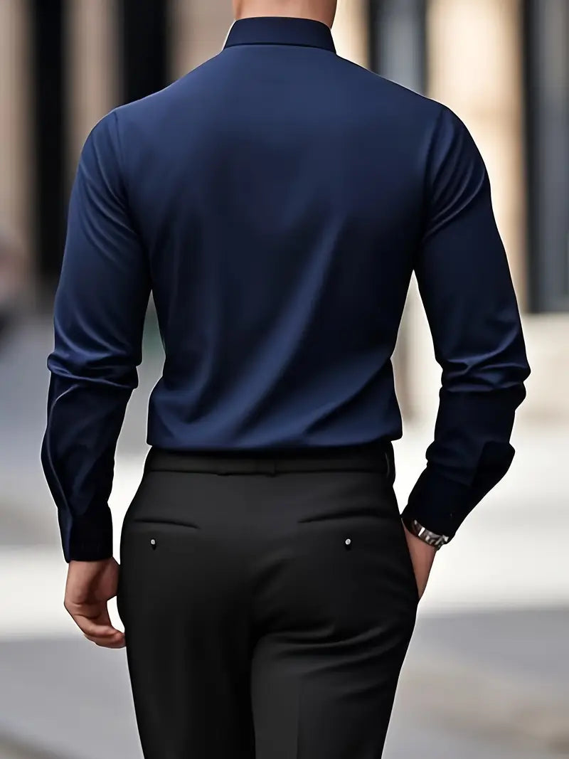 Rückansicht eines Mannes in dunkelblauem Hemd und schwarzer Hose, gehend auf städtischem Gehweg. Businessmode, Herrenbekleidung, eleganter Stil.