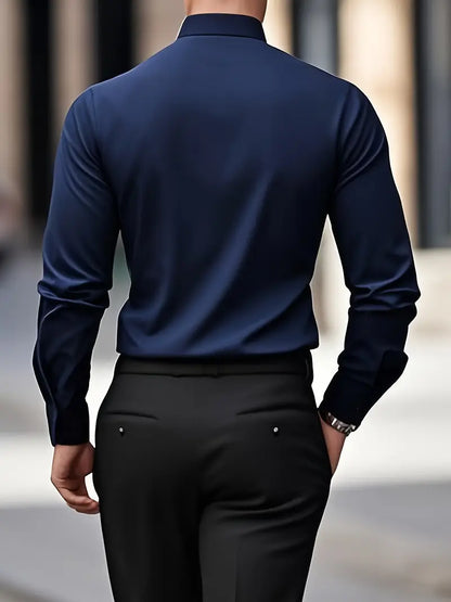 Rückansicht eines Mannes in dunkelblauem Hemd und schwarzer Hose, gehend auf städtischem Gehweg. Businessmode, Herrenbekleidung, eleganter Stil.