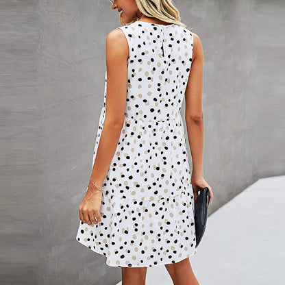 Frau in ärmellosem, weißem Kleid mit schwarzen Punkten, seitlich stehend, grauer Hintergrund. Sommermode, elegantes Design, Freizeitkleidung.