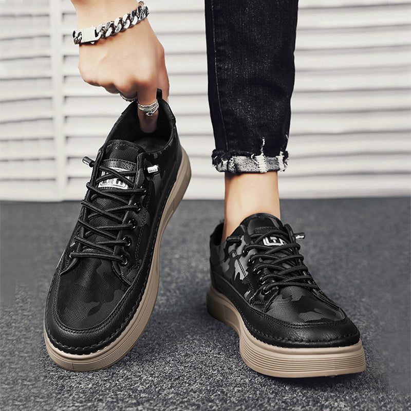 Schwarze Camouflage-Sneaker mit dicker Sohle, getragen von Person in Jeans. Modische Herrenschuhe, urbaner Stil, Nahaufnahme.