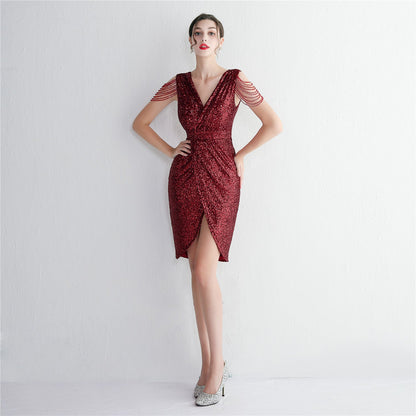 Frau in elegantem, rotem Paillettenkleid mit V-Ausschnitt und Perlenärmeln, posiert vor weißem Hintergrund. Abendmode, Cocktailkleid, Damenmode.