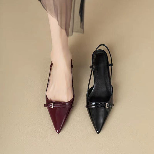 Damenfüße in eleganten spitzen Slingback-Pumps, ein Schuh in Bordeauxrot, der andere in Schwarz, auf beigem Hintergrund. Modetrend, Damenschuhe.