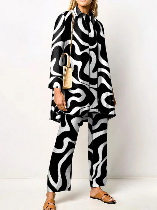 Frau in schwarz-weiß gemustertem Anzug, trägt beigefarbene Sandalen und eine goldene Umhängetasche. Modetrend, geometrisches Design, stilvoll.
