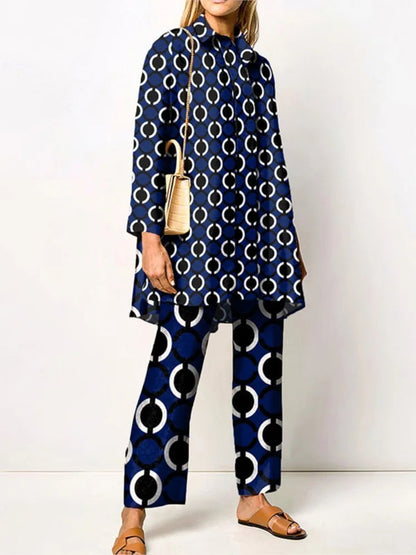 Frau in blauem, gemustertem Anzug mit Kreisen, beiger Umhängetasche und braunen Sandalen. Modetrend, Damenmode, elegantes Outfit.