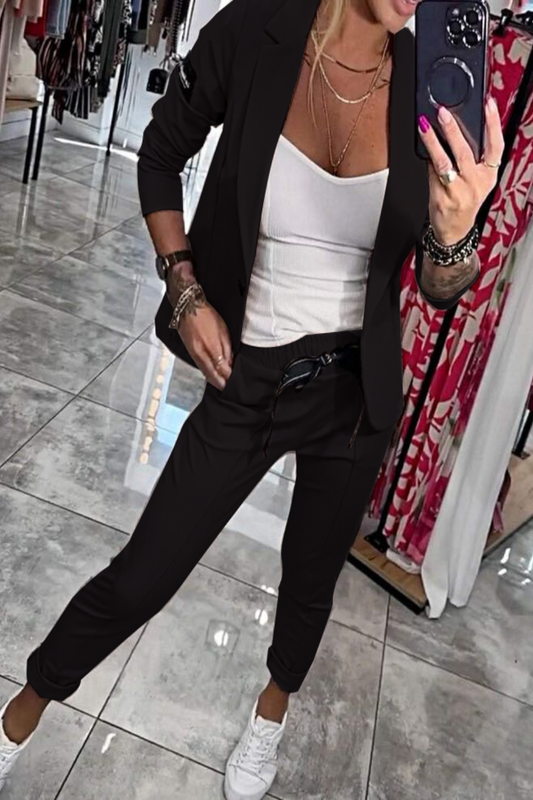 Frau in schwarzem Anzug und weißem Top macht Selfie in Boutique. Modische Kleidung, Business-Look, Spiegelbild, moderne Damenmode.