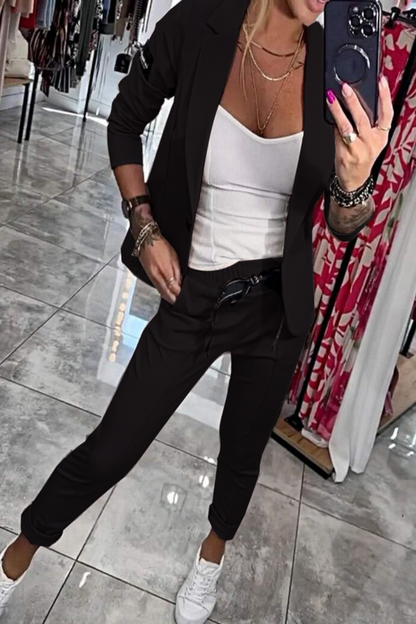 Frau in schwarzem Anzug und weißem Top macht Selfie in Boutique. Modische Kleidung, Business-Look, Spiegelbild, moderne Damenmode.