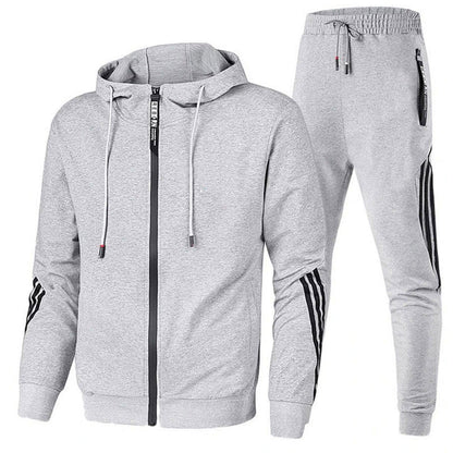 Grauer Herren-Trainingsanzug mit Kapuzenjacke und Jogginghose, schwarze Streifen an Ärmeln und Beinen, Reißverschluss, sportlich, bequem.