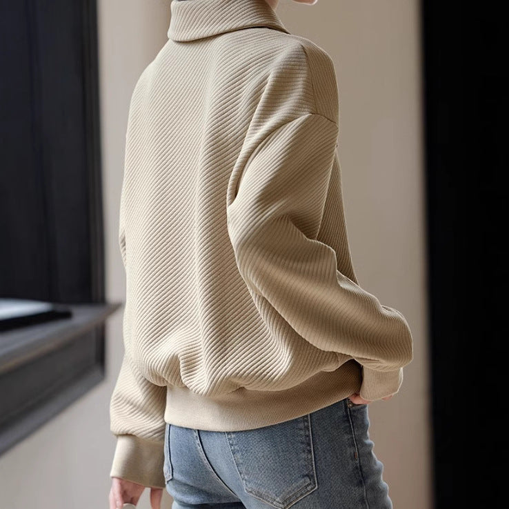 Beige Rollkragenpullover aus geripptem Stoff, getragen von einer Person, kombiniert mit blauen Jeans. Modetrend, Herbstmode, lässiger Stil.