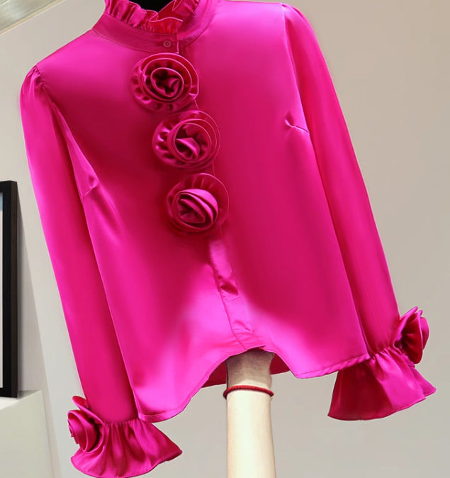 Pinkfarbene Seidenbluse mit Rüschen und Blumenverzierungen, elegantes Design, modische Damenbekleidung, stilvolle Bluse für besondere Anlässe.