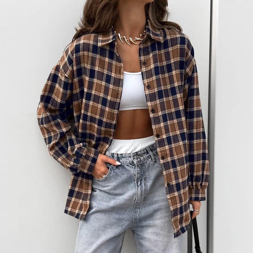 Frau trägt karierte Oversize-Hemdjacke, weißes Crop-Top und Jeans. Modetrend, lässiger Streetstyle, Herbstmode, Damenbekleidung.
