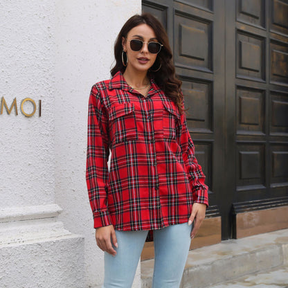 Frau in rotem Karohemd und blauer Jeans vor Holztür, trägt Sonnenbrille und Ohrringe. Modetrend, lässiger Stil, Herbstmode.