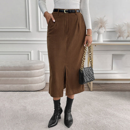 Frau in braunem Cordrock und weißem Pullover, schwarze Stiefeletten, schwarze gesteppte Handtasche mit goldener Kette, elegantes Outfit, Mode.