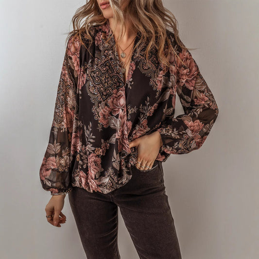 Frau trägt schwarze, geblümte Bluse mit langen Ärmeln und V-Ausschnitt, kombiniert mit dunkler Hose. Modetrend, Damenmode, Herbstoutfit.