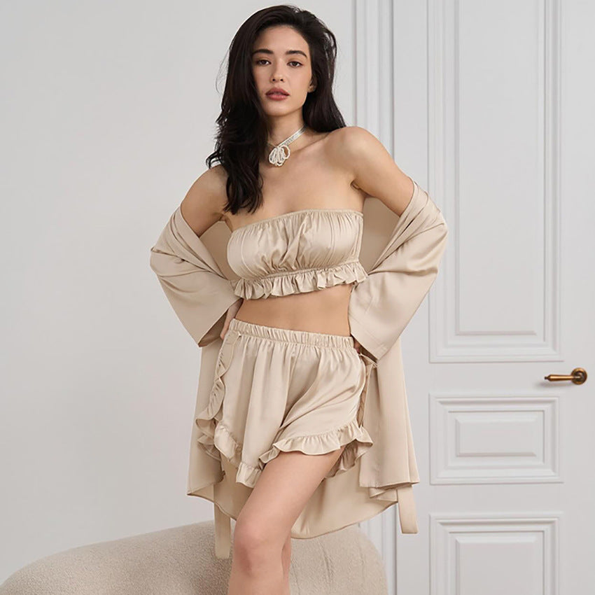 Frau in beigem, schulterfreiem Set mit Shorts und Kimono vor weißer Tür. Modetrend, Sommeroutfit, eleganter Look, Damenbekleidung.