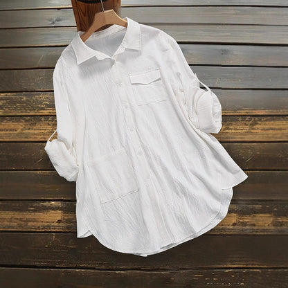 Weiße Damenbluse aus Baumwolle, lässig geschnitten, mit Brusttasche und hochgekrempelten Ärmeln, auf Holzhintergrund. Ideal für Freizeitmode.