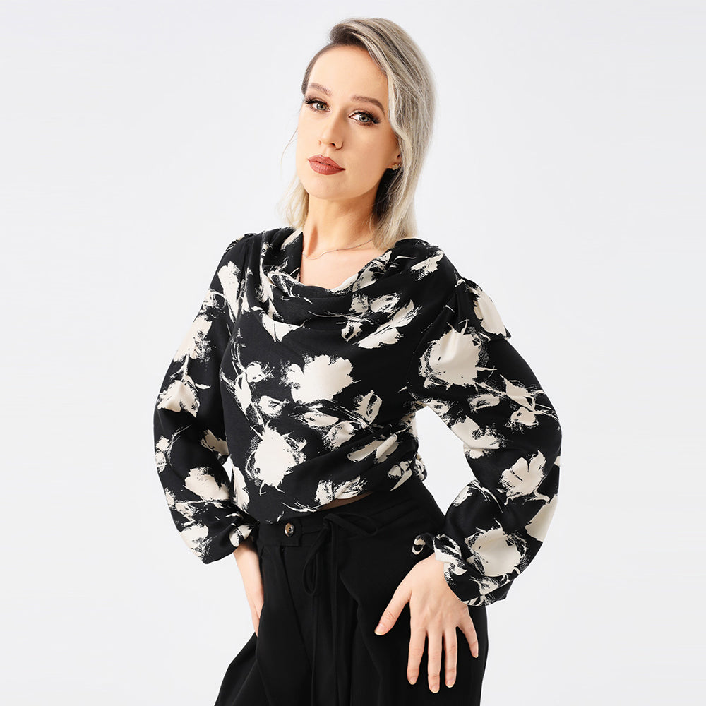 Frau in schwarzer Bluse mit weißem Blumenmuster, posiert vor weißem Hintergrund. Modetrend, Damenmode, stilvolle Kleidung, elegantes Design.