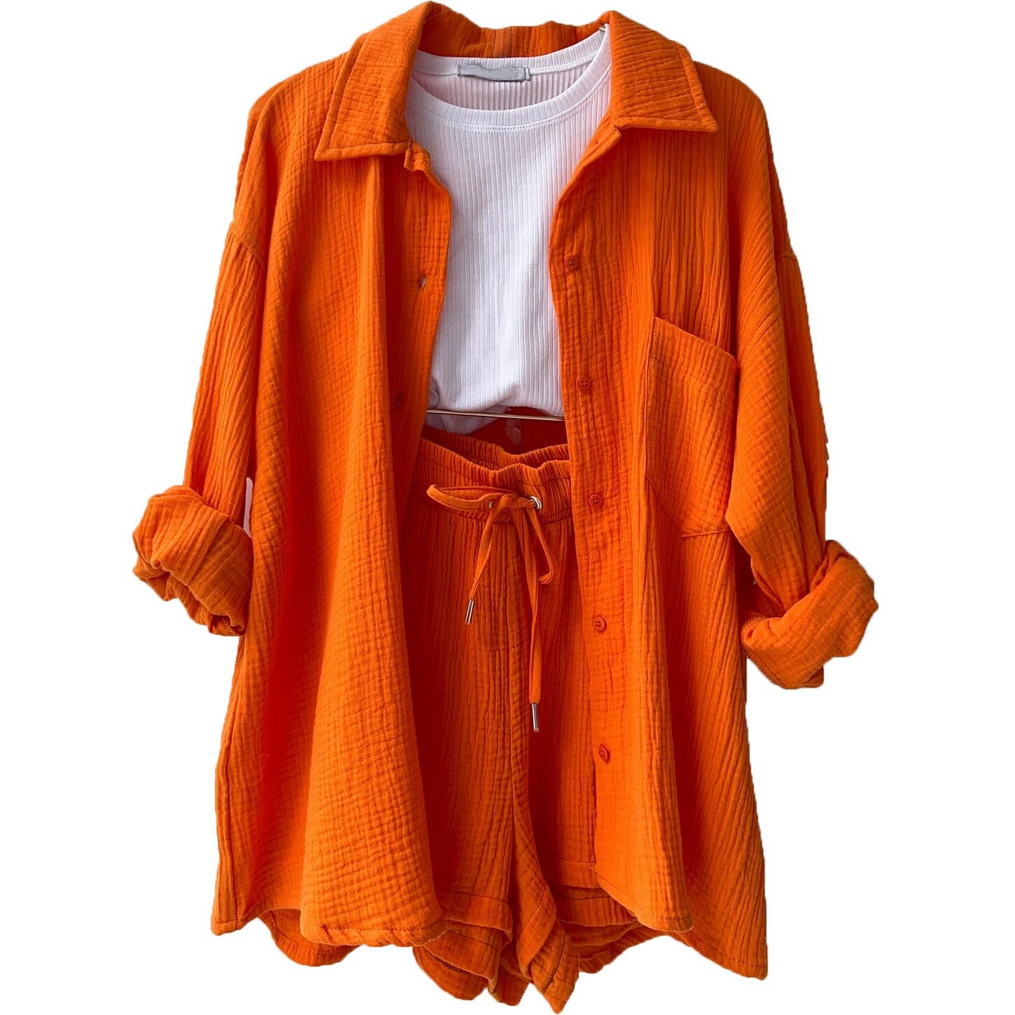 Orangefarbener Damen-Zweiteiler aus Baumwolle, bestehend aus Hemd und Shorts, kombiniert mit weißem T-Shirt. Modetrend, Sommeroutfit, Freizeitkleidung.
