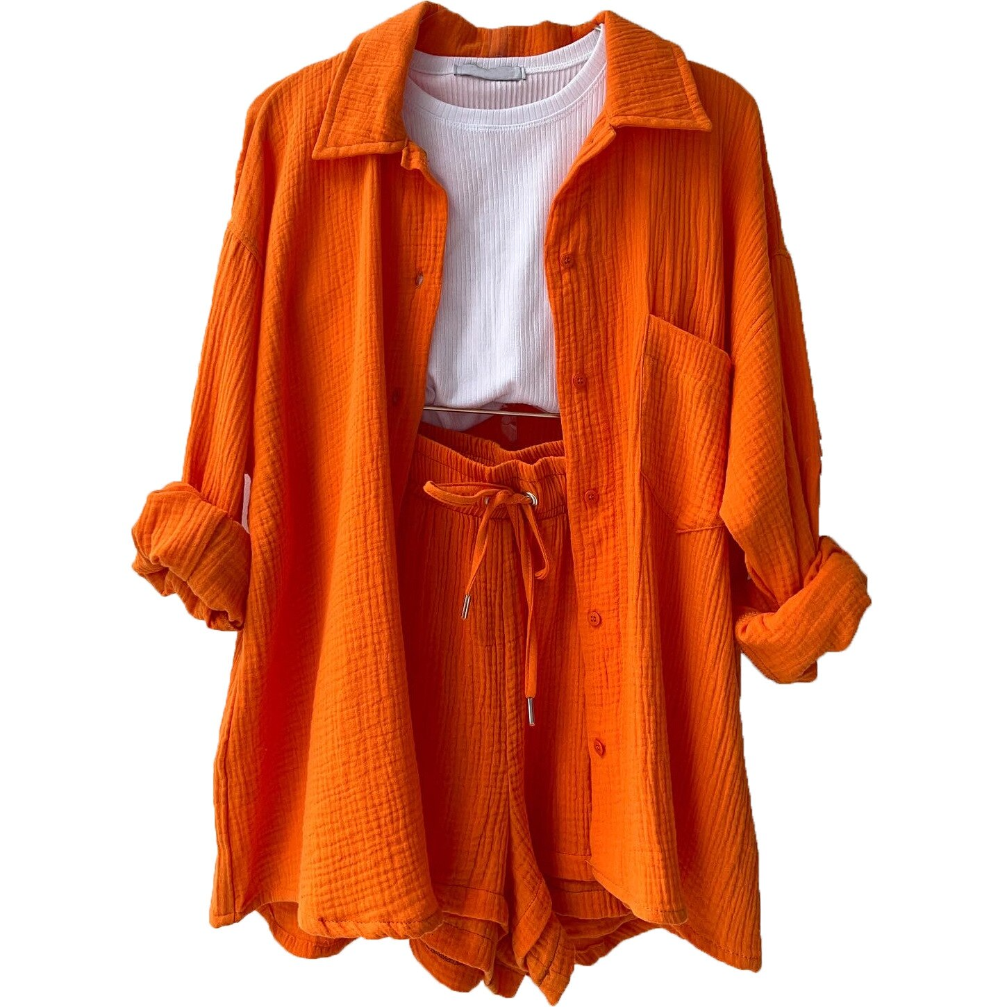 Orangefarbener Damen-Zweiteiler aus Baumwolle, bestehend aus Hemd und Shorts, kombiniert mit weißem T-Shirt. Modetrend, Sommeroutfit, Freizeitkleidung.