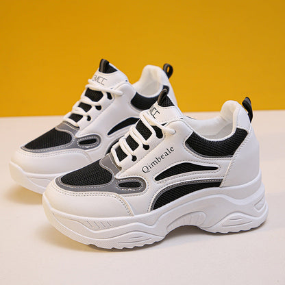 Weiße und schwarze Damen-Sneaker mit dicker Sohle vor gelbem Hintergrund. Modische Turnschuhe, atmungsaktiv, ideal für Freizeit und Sport.