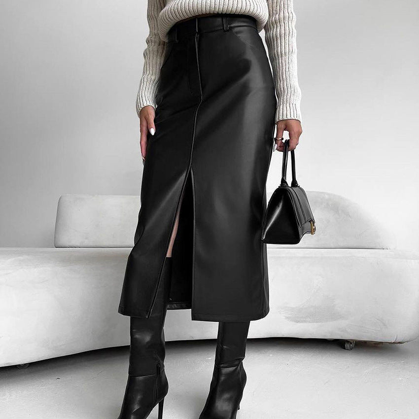 Frau in schwarzem Lederrock mit Schlitz, cremefarbenem Strickpullover und Stiefeln, hält schwarze Handtasche. Elegante Mode, Herbst-Outfit.