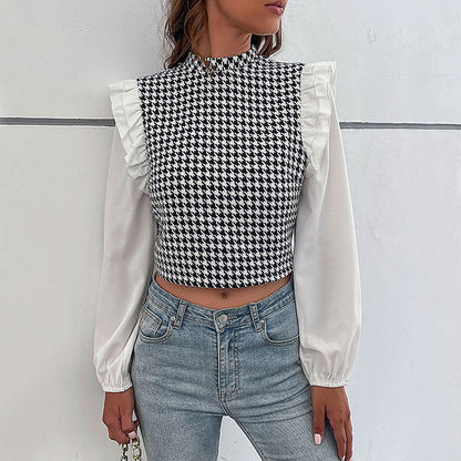 Frau trägt schwarz-weiß kariertes Oberteil mit Rüschen und weiße Ärmel, kombiniert mit blauen Jeans. Modetrend, stilvolles Outfit, Streetwear.