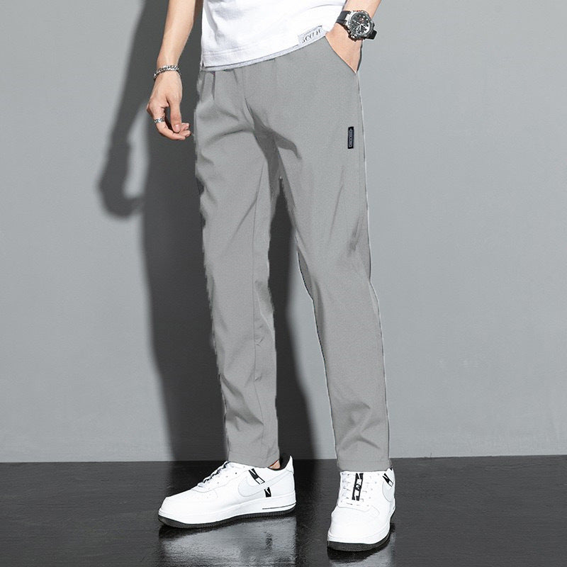 Graue Herren-Chinohose, lässig geschnitten, kombiniert mit weißen Sneakers und weißem T-Shirt, ideal für modische Freizeitoutfits.