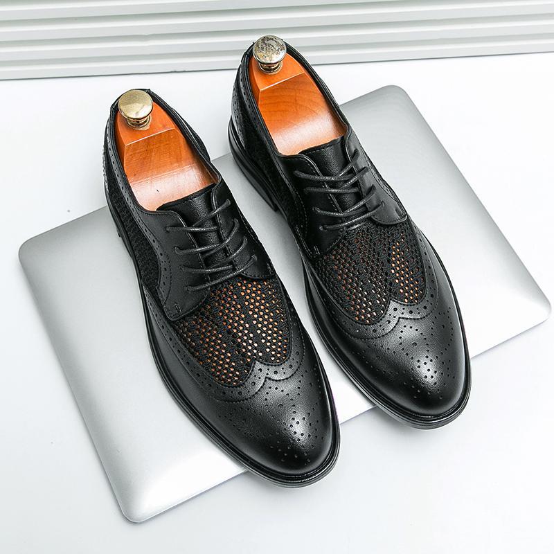 Schwarze Herren-Brogues aus Leder mit Lochmuster auf silbernem Laptop. Elegante Business-Schuhe, ideal für formelle Anlässe und Büro.