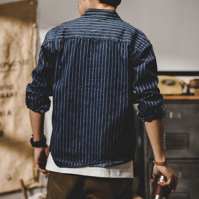 Mann in gestreiftem, dunkelblauem Jeanshemd von hinten, lässiger Stil, hochgekrempelte Ärmel, urbanes Outfit, modische Herrenbekleidung.